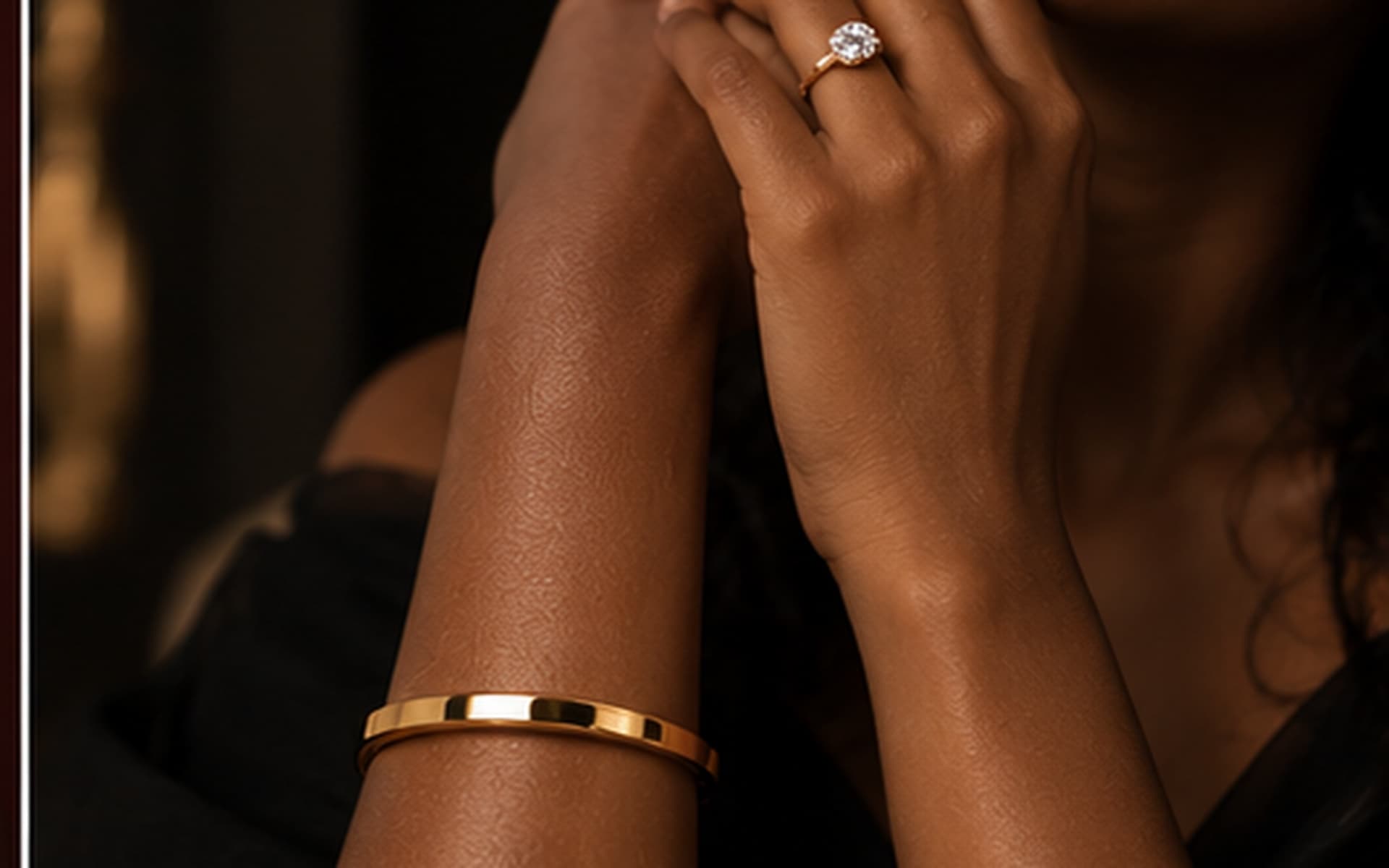 Woman with curly hair wearing fringe drop earrings and a gold cuff, moody red studio lighting
