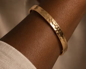 Hammered-texture gold bangle, worn on the wrist