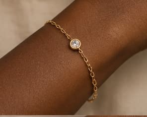 Fine gold chain bracelet with a charm, worn on the wrist