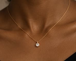 Fine gold necklace with a small pendant, worn at the collarbone
