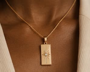 Gold bar pendant on a fine chain, worn at the collarbone